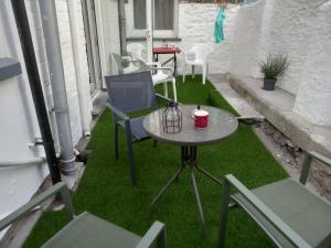 a small table and chairs on a patio with grass at 52 Cambrian St in Aberystwyth