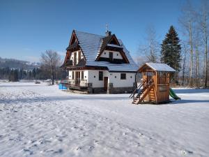 een huis met een speeltuin in de sneeuw bij Jurgowski Domek in Jurgów