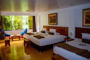 a hotel room with two beds and a table and chairs at Hotel Tara Machupicchu in Machu Picchu