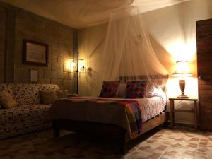 um quarto com uma cama e um sofá em Hotel Posada Rancho Los Laureles 