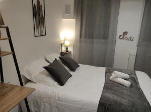 Un dormitorio con una cama blanca con almohadas negras. en Villa Raphaëlle #5 Centre ville avec parking, en Le Havre