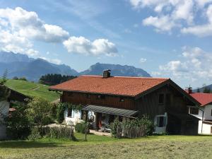 a house with a red roof with mountains in the background at Haus Klauser in Reit im Winkl