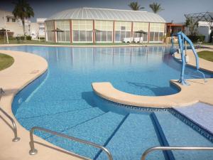 une grande piscine d'eau bleue en face d'un bâtiment dans l'établissement Bahia de Vera Apartamento Flamingo, à Playas de Vera