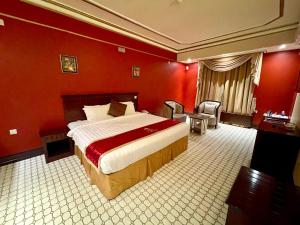 a bedroom with a large bed in a red room at Al Mansour Grand Hotel in Hafr Al Baten