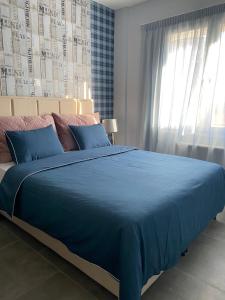 a bed with a blue blanket and a window at CASA MILITOU-NEA FILADELFIA in Athens