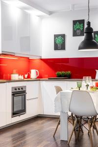 a kitchen with white cabinets and a red wall at Apartament w Centrum Ostróda in Ostróda