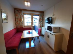 a small room with a red couch and a table at Apart Kofler's Panorama-Zillertal in Fügen