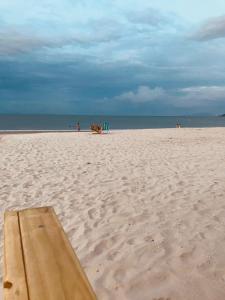 uma tábua de madeira numa praia arenosa com o oceano em Light Beach Residence em Florianópolis