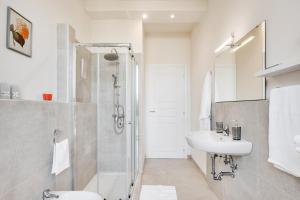 La salle de bains blanche est pourvue d'une douche et d'un lavabo. dans l'établissement AriediParma Appartamenti, à Parme