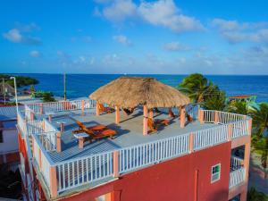 a building with a large umbrella and chairs and the ocean at Caye Caulker Condos in Caye Caulker