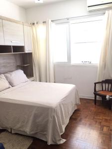 a bedroom with a bed and a window and a chair at Pé na areia em Santos in Santos