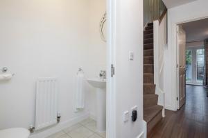 a white bathroom with a sink and a staircase at Stunning 3BR house in Basildon in Basildon