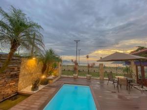 uma piscina num quintal com uma mesa e cadeiras em Casa Melville Hospedagem - Sua Casa de Alto Padrão no Coração de Ubatuba! em Ubatuba