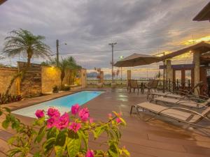 a swimming pool with chairs and pink flowers at Casa Melville Hospedagem - Sua Casa de Alto Padrão no Coração de Ubatuba! in Ubatuba