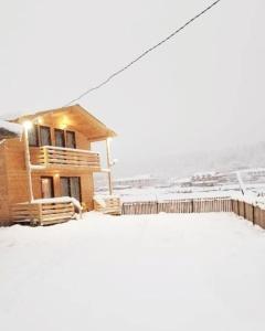 a house covered in snow in front of a fence at Villa GabLile in Mestia