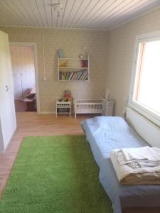 1 dormitorio con cama y alfombra verde en Laukkumäki farm, en Iisalmi