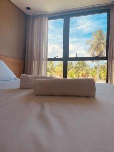 a bedroom with a large bed with a large window at Housi, condo beira mar em Milagres in Passo de Camarajibe