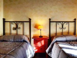 Duas camas num quarto com um candeeiro numa cómoda em Le Torri San Gimignano Apartments em San Gimignano