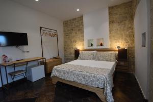 a bedroom with a bed and a desk and a television at B&B Cuore Barocco in Ragusa