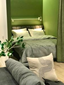 ein Schlafzimmer mit einem Bett mit einer grünen Wand in der Unterkunft Modern Studio City Center дуже затишно! in Chmelnyzkyj