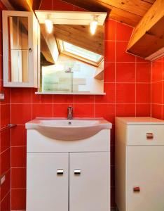 La salle de bains est pourvue d'un lavabo et d'un mur rouge. dans l'établissement IL VILLAGGIO DELLE FATE, à Macerata