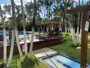 a resort with a swimming pool and palm trees at Linda casa em condomínio Sun House Maresias com piscina - 50 m da praia in Maresias