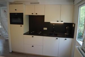 a kitchen with white cabinets and a black counter top at ArdennenVakantieBungalow in Durbuy