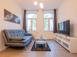 un salon avec un canapé bleu et une télévision dans l'établissement EUPHORAS - Geschmackvolles Apartment in Hannover, à Hanovre