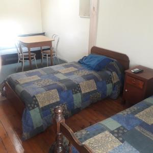 two beds in a room with a table and a table at Hostal Rayen in Villarrica