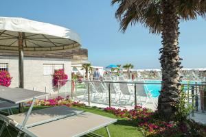 a patio with tables and a palm tree and a pool at Hotel Diamond NUOVA GESTIONE in Riccione