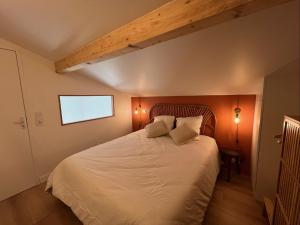 a bedroom with a large white bed with a wooden headboard at Les Embruns, océan et centre ville à pied in Capbreton