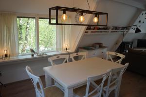 ArdennenVakantieBungalow في دربي: غرفة طعام مع طاولة بيضاء وكراسي