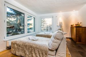 a bedroom with two beds and a couch and windows at Waldhotel Fletschhorn Saas-Fee in Saas-Fee