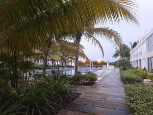 una piscina con palmeras junto a un edificio en Relajate en un hermoso apartamento Duplex cerca de la playa y piscina en Playa Blanca, Farallon, en Río Hato