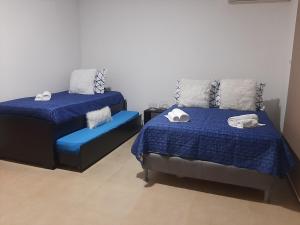 1 dormitorio con 2 camas con sábanas azules y silla en Relajate en un hermoso apartamento Duplex cerca de la playa y piscina en Playa Blanca, Farallon en Río Hato