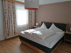 - une chambre avec un lit doté de draps blancs et une fenêtre dans l'établissement Schusslerhof, à Sankt Leonhard im Pitztal