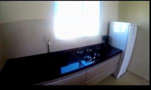 a kitchen with a black counter and a refrigerator at Vilas na Praia Residence Canoa Quebrada CE Apartamento PÉ NA AREIA superior com 2 suítes, vista para a Praia e Dunas e com privacidade total in Canoa Quebrada
