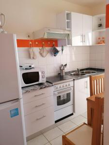 a kitchen with white cabinets and a microwave at Family Apartment in Praia