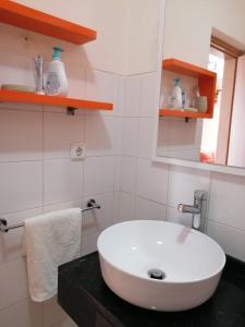 La salle de bains est pourvue d'un lavabo blanc et d'un miroir. dans l'établissement Family Apartment, à Praia