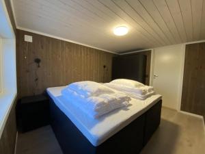 a bed with white sheets and pillows in a room at Hytte nær vannet, jacuzzi og sauna in Vradal