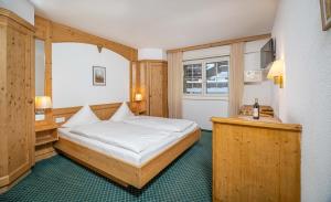 a bedroom with a bed and a desk and a window at Grichting Hotel & Serviced Apartments in Leukerbad +261 photos