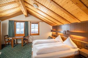 a bedroom with a bed and a desk in it at Grichting Hotel & Serviced Apartments in Leukerbad