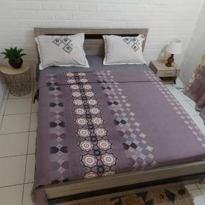 Una cama con una manta púrpura y almohadas. en LÃCAZÈRĂ Sãfãrì, en Mamoudzou