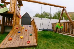 a wooden play set with swings and a playground at Buturuga Mică in Nehoiu