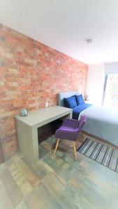 een slaapkamer met een bed en een bureau met een paarse stoel bij R08 LUXURY STUDIO RAISE a 5 MIN DEL ITESM R08 in Mexico-Stad