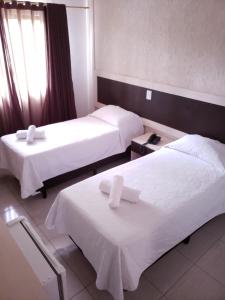 Habitación de hotel con 2 camas con sábanas blancas en Hotel Castelo Branco en Foz de Iguazú