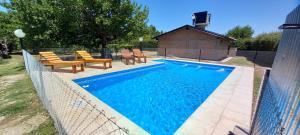 a swimming pool with chairs and a fence around it at Casita Rural Los Abuelos in San Rafael