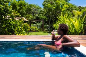 a young girl sitting in a pool drinking a drink at Bahia Soul - Flow Beach House - Taipu de Fora - Península de Maraú in Barra Grande