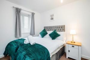 a bedroom with a large bed with a green blanket at Stunning 3BR house in Basildon in Basildon