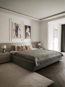 een slaapkamer met een groot bed met twee foto's aan de muur bij Modern Classic 2 bedroom apartment near Most City in Dnipro